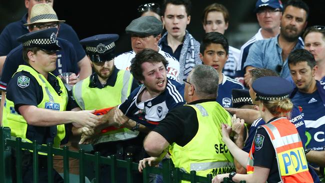 SA Police and a security guard escort a Melbourne Victory fan out of Adelaide Oval during a 2015 A-League game. Picture: Sarah Reed