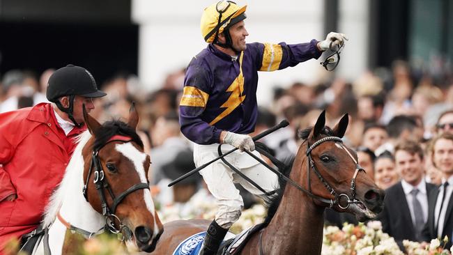 Jockey Dwayne Dunn throws his goggles into the crowd at Flemington on Derby day. Picture: AAP