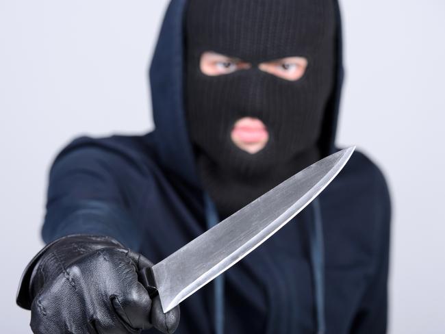 Masked man aims with knife. on gray background. Robbery, crime, knife generic