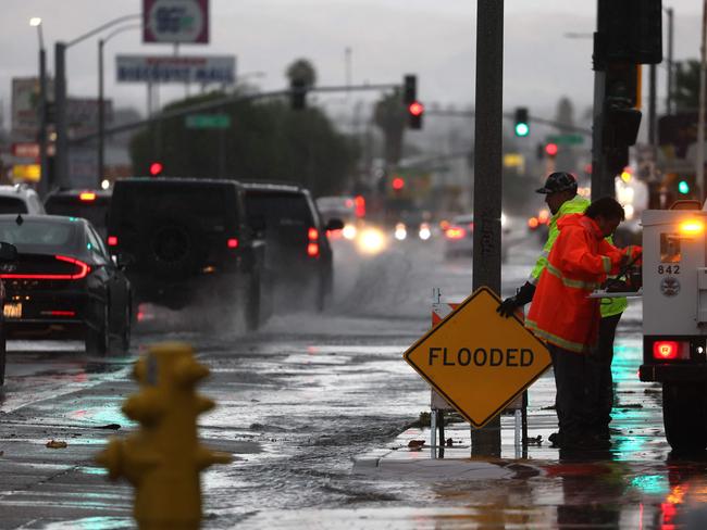 Workers set up a sign near a flooded intersection as Tropical Storm Hilary moves through San Bernardino, California. Southern California. Picture: AFP