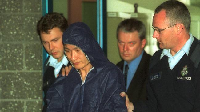 Police lead the gunman Huan Yun Xiang from Glen Waverley Police station.