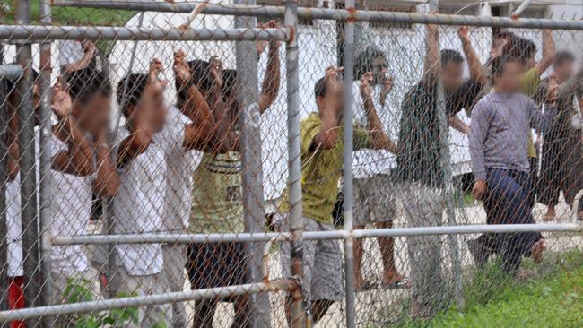 Asylum seekers standing behind a fence at the Manus Island detention centre in Papua New Guinea last month. Picture: AAP Image/Eoin Blackwell