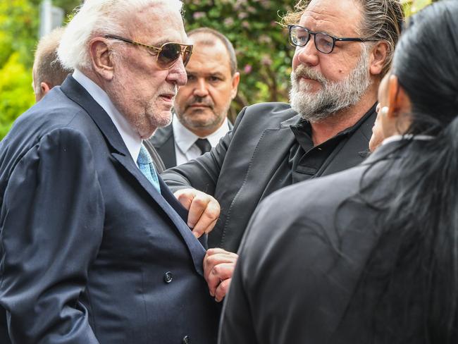 Actor Russell Crowe assists John Laws (left) outside the funeral service for Caroline Laws at St Mark's Church in Sydney. Picture: AAP