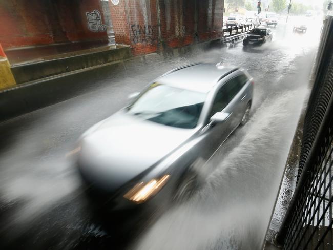 A car drives under the rail bridge in Melbourne where the Bureau of Meteorology is predicting the city could get one month's worth of rain in just two days. Picture: Darrian Traynor/Getty Images.