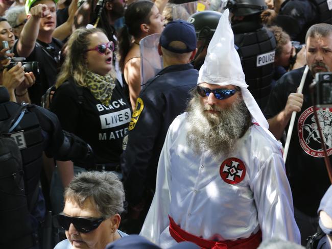 This July 8, 2017 photo shows members of the KKK escorted by police past a large group of protesters during a KKK rally in Charlottesville, Va.  Some white Southerners are again advocating for what the Confederacy tried and failed to do in the 1860s: secession from the Union. So-called Southern nationalists are within the group of demonstrators who are fighting the removal of Confederate monuments around the South. They say itâ€™s time for Southern states to secede again and become independent of the United States..(AP Photo/Steve Helber)