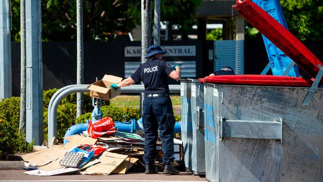 A police officer searches a skip bin near the scene. Picture: Che Chorley