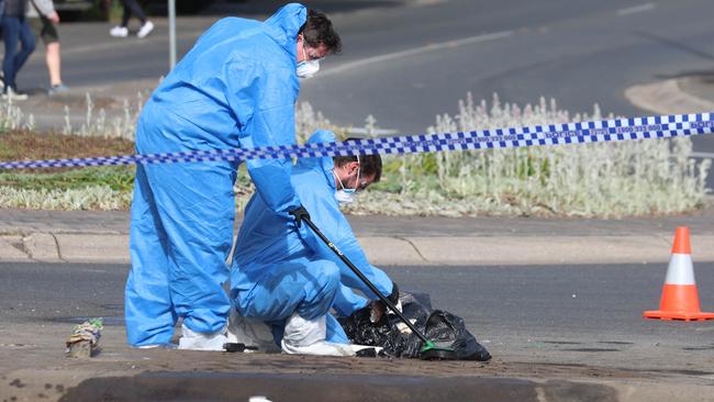 Investigators in blue hazmat suits and face masks scrub and examine the road and debris. Picture: Brendan Beckett