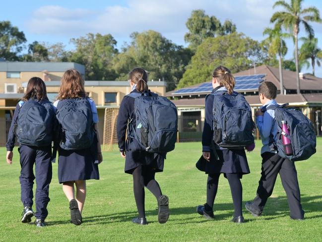 Group of Australian school students wearing school uniform walking together to school in the morning time.