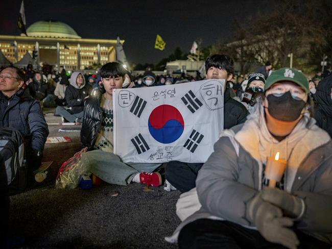 SEOUL, SOUTH KOREA - DECEMBER 07: Protesters watch a television broadcast of proceedings taking place at the National Assembly as they take part in a protest against the South Korean president on December 07, 2024 in Seoul, South Korea. South Korean lawmakers are set to vote on the impeachment of President Yoon Suk Yeol on Saturday, following his controversial declaration of martial law, which sparked widespread public outrage and political turmoil. (Photo by Ezra Acayan/Getty Images)