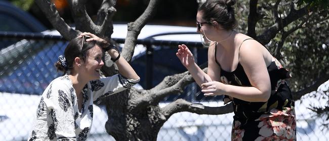 A spectator rubs her head after being struck by the ball at Brighton Beach Oval.