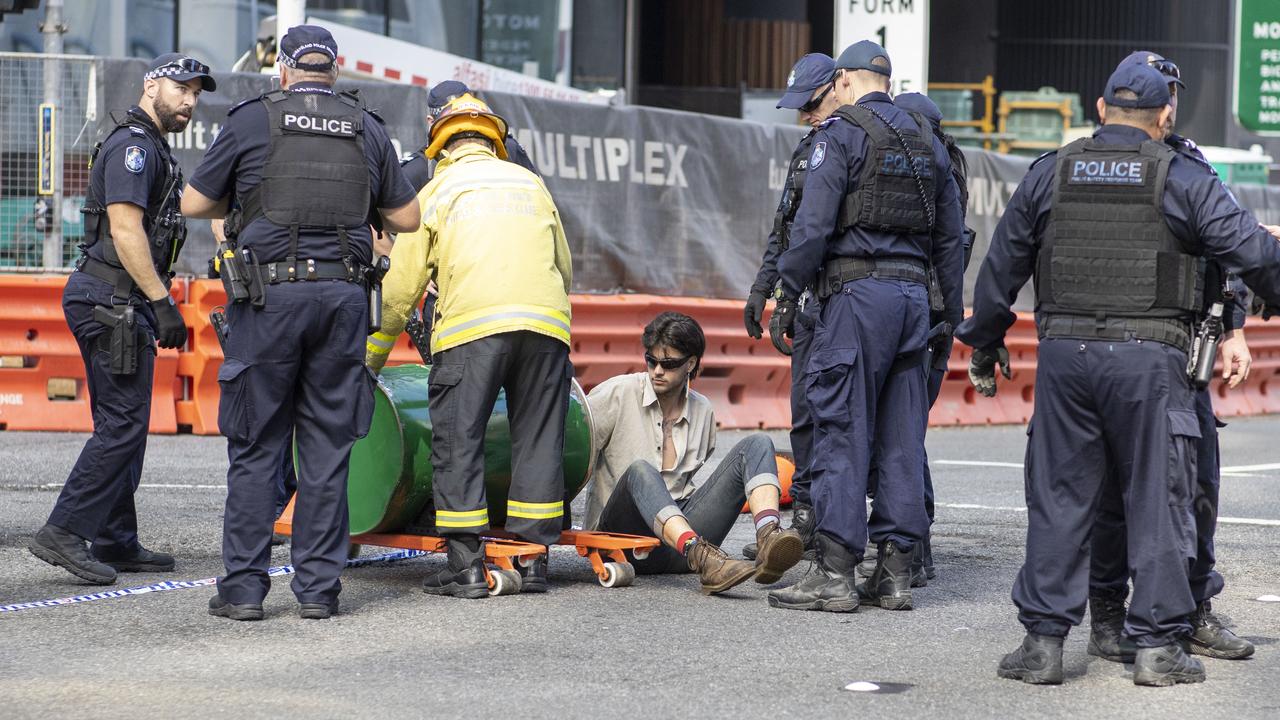 An activist from Extinction Rebellion with his arm in a barrel of cement blocks an intersection in Brisbane. Picture: AAP