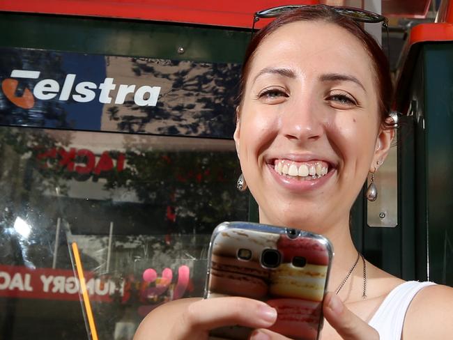 pic shows left Maddi Vantarakis and Zoe Keigtley on their phones browsing online next to theTelstra phone box in Swanston st . Telstra has rolled out free wi fi on their phone boxes across the state.