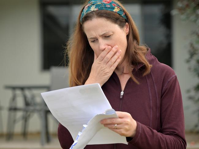 An upset adult woman (female age 25-35) reading a letter in home front yard.bill shock, woman shocked generic money