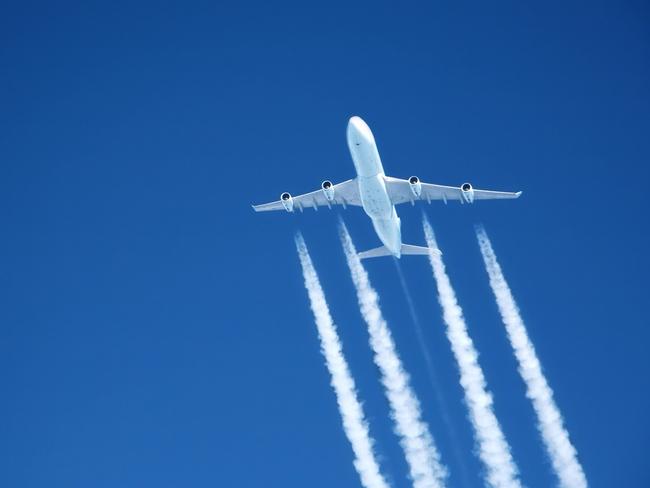 contrails streaming from a jumbo jet on blue sky at altitude