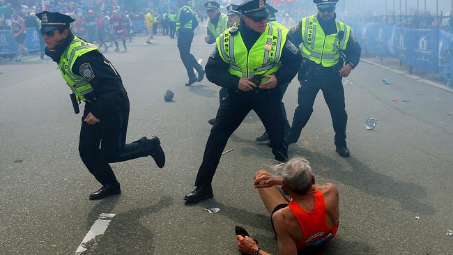 Bill Iffrig, 78, lies on the ground as police officers react to a second explosion at the finish line of the Boston Marathon in 2013. Picture: AP