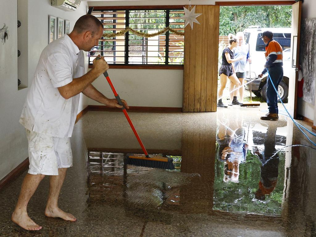 Garry Henry sweeps floodwater out from a house at Caravonica, Cairns. Picture: Brendan Radke