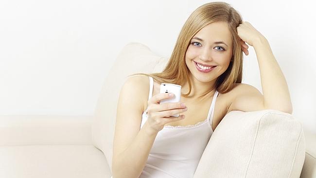 Generic image of happy woman using mobile phone smartphone device on couch.