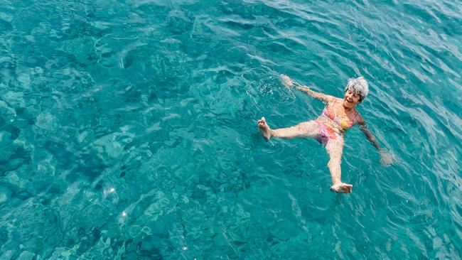 Senior woman has a fun in turquoise sea water top view.