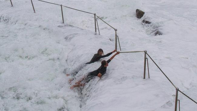 Two teenagers ignore the storm warnings, by risking their lives at Bronte Beach, Sydney, Australia. Picture: Bill Morris