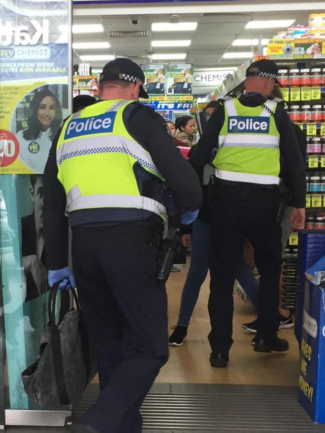 Police carry a bag, believed to have been found on the roof, into the My Chemist store. Picture: Andrea Hamblin.