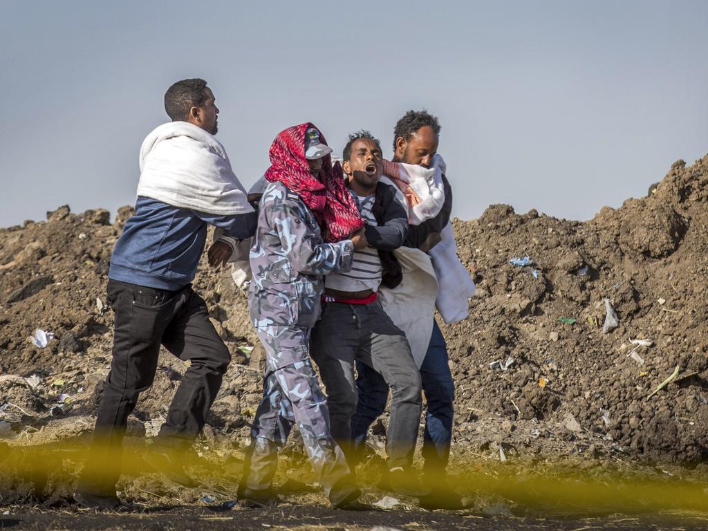 A grieving relative who lost his wife in the plane crash is helped by a member of security forces and others near Bishoftu, in Ethiopia, near where the plane crashed. Picture: AP/Mulugeta Ayene