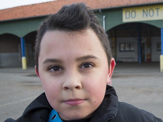 Raphael Teixera, 10, pictured at La Ecole Victoria (Victoria School) in the village of Villers-Bretonneux in France. In the courtyard a banner demanding Do Not Forget Australia. Picture: Ella Pellegrini