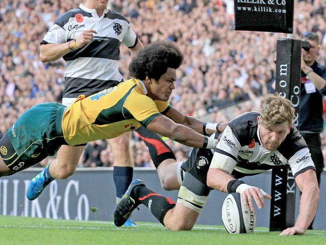 Adam Thomson of the Barbarians scores a try in the corner despite the tackle of Wallabies winger Henry Speight.