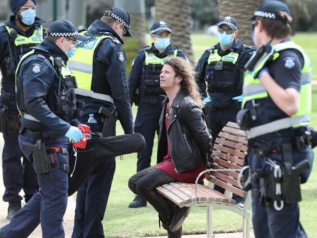 A man who has been seen at previous protests sing with a guitar, is temporarily detained by police. A large number of police keep an eye on Catani Gardens in St Kilda for anti lockdown protesters. Saturday, September 26, 2020. Picture: David Crosling