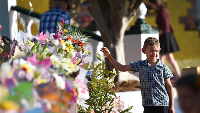 Dreamworld - young boy places flowers at Dreamworld the day after the tragedy where four people were killed. Picture: Nigel Hallett