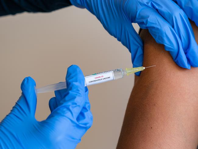 This picture depicts a young female clinician using a syringe to inject a concept COVD-19 liquid vaccine into a young girl patient during the Phase 3 vaccination human trials.