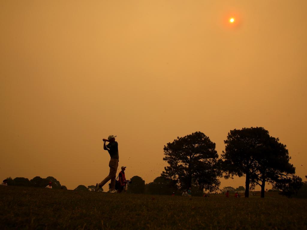 Adam Scott hits to the 18th under a smoky haze.