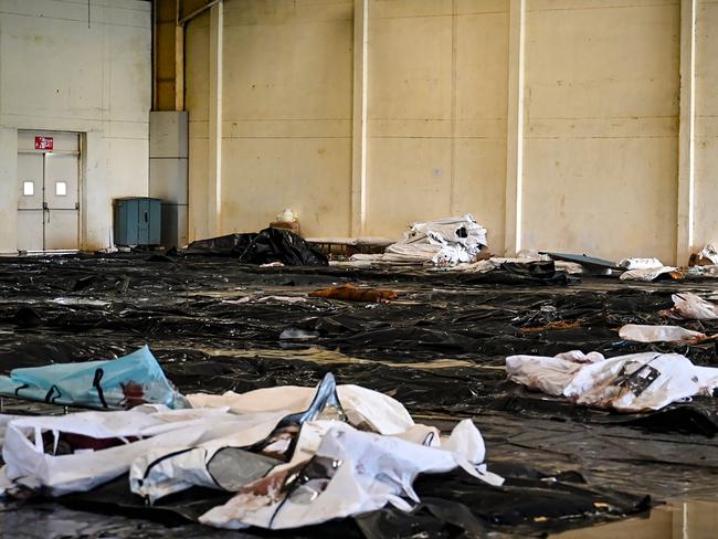 A rescue worker walks past victims' bodies at a business park used as temporary mortuary to identify the dead recovered from the wreckage of a three-train collision. Picture: AFP