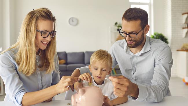 Child puts money inside piggy bank, learns to effectively manage budget and spend wisely from young independent parents able to provide high living standard. bank of mum and dad, kids financial literacy concept