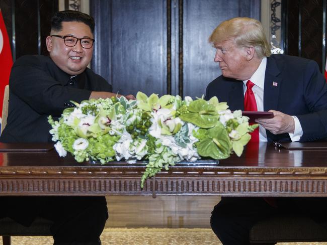 US President Donald Trump looks at North Korean leader Kim Jong-un after signing the document. Picture: AFP