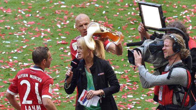 Bayern Munich's Dutch midfielder Arjen Robben pours beer over a TV reporter as she interviews Bayern Munich's defender Philipp Lahm (L).