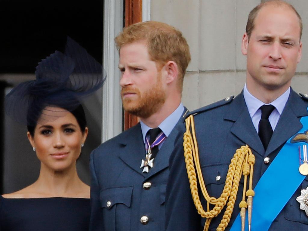 Meghan, Duchess of Sussex, Britain's Prince Harry, Duke of Sussex, and Britain's Prince William, Duke of Cambridge, stand on the balcony of Buckingham Palace to watch a military fly-past to mark the centenary of the Royal Air Force (RAF).