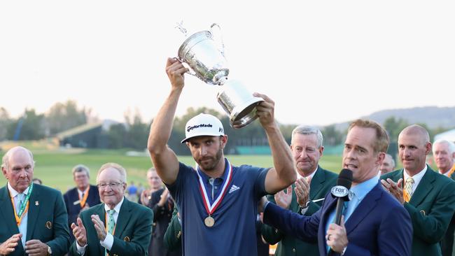 Dustin Johnson poses with the winner's trophy.