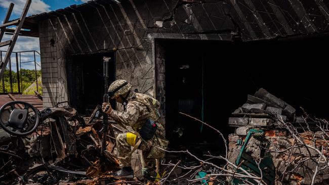 A soldier of the Kraken Ukrainian special forces unit walks past wreckage in the village of Rus'ka Lozova, north of Kharkiv. Picture: AFP.