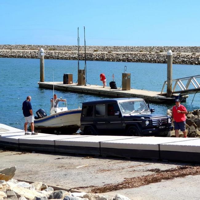 Stephen Marks (red top) and associates towing a boat from the Marina St Vincent on Monday.