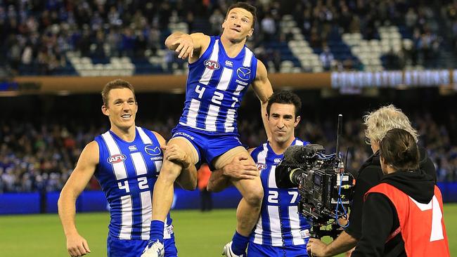 Brent Harvey is chaired off by Drew Petrie and Michael Firrito. Picture: Wayne Ludbey