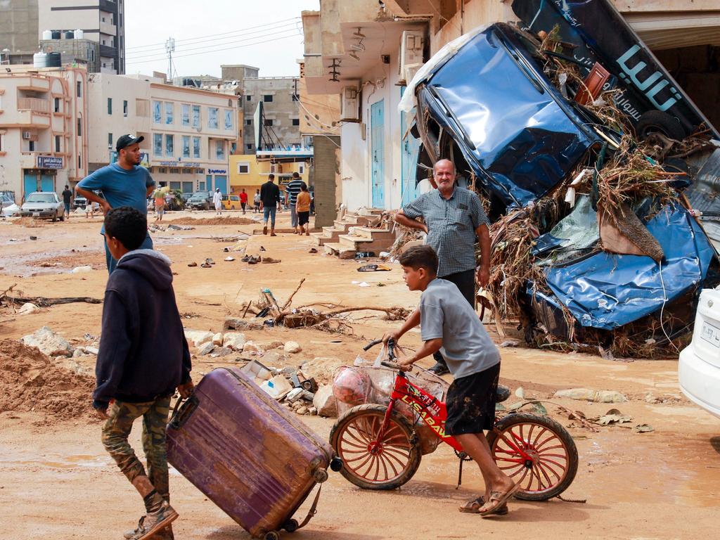 A boy pulls a suitcase past debris in a flash-flood damaged area in Derna. (Photo by AFP)