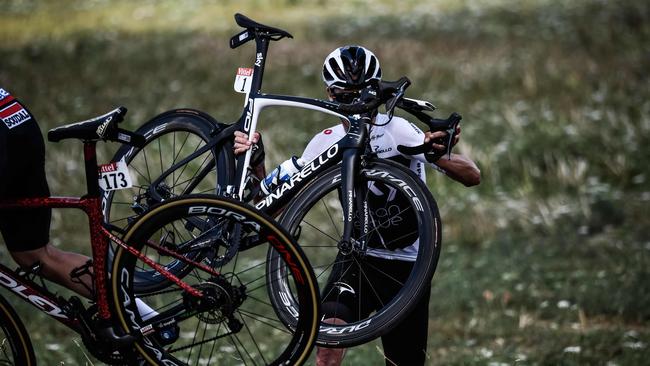 Great Britain's Chris Froome carries his bicycle after falling into a ditch in the last kilometres of the first stage of the 105th edition of the Tour de France. Photo: AFP