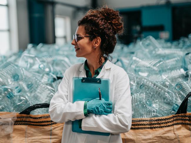 Young happy female worker in bottling factory recycling department. Inspection quality control.