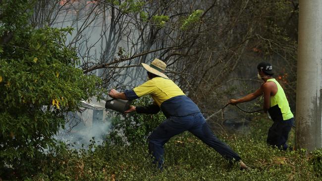 Two people try desperately to keep encroaching flames at bay in Lithgow. Picture: Tim Hunter