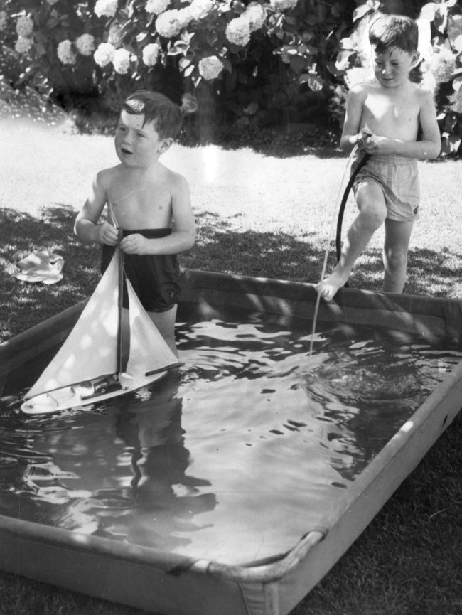 Boys play with a toy boat in a wading pool in 1958.