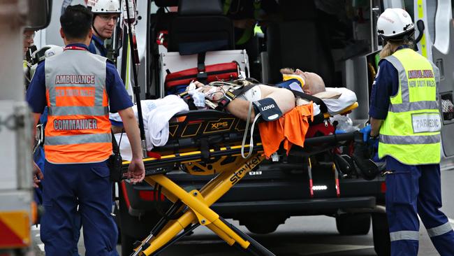 Paramedics stretcher a seriously injured man to ambulance. Picture: Adam Yip