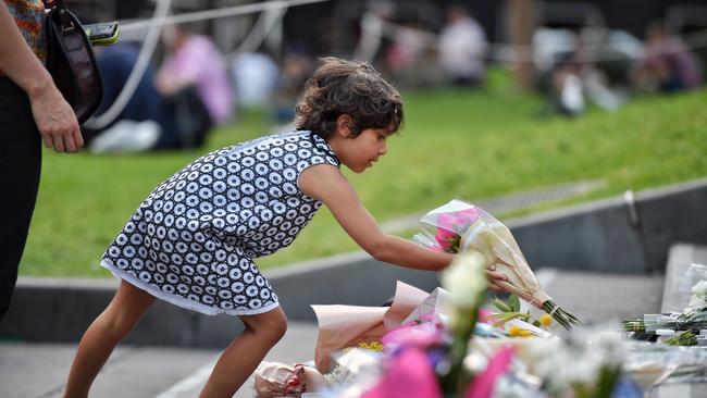 A girl places flowers for victims of the Christchurch massacre in front of Melbourne’s State Library. Picture: Jason Edwards