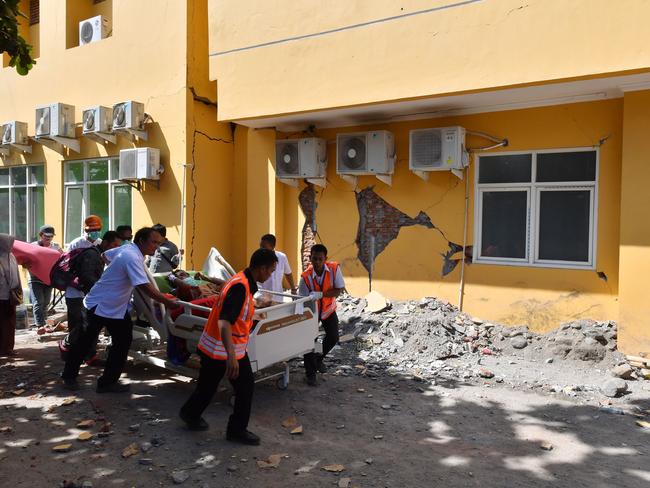 A man is wheeled passed a damaged wall to a makeshift ward. Picture: AFP