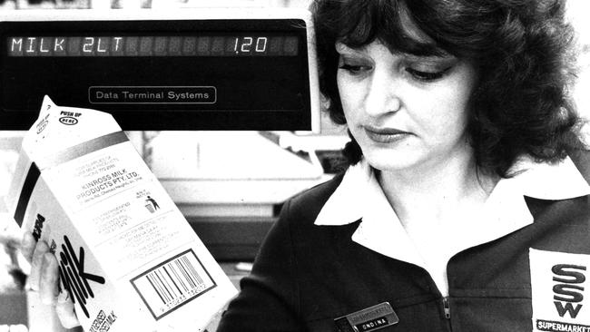 A cashier inspects a new barcode on a milk carton at SSW Supermarkets in 1982.