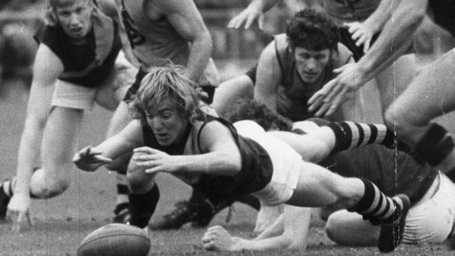 Glenelg’s Kym Hodgeman dives on the ball in the 1974 grand final, watched by, from left, Bob Tardif, Mick Nunan, Greg Wild and Peter Obst (hidden).